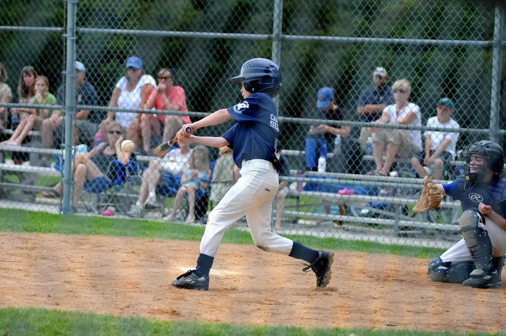 A young player mid-swing at bat during a game
